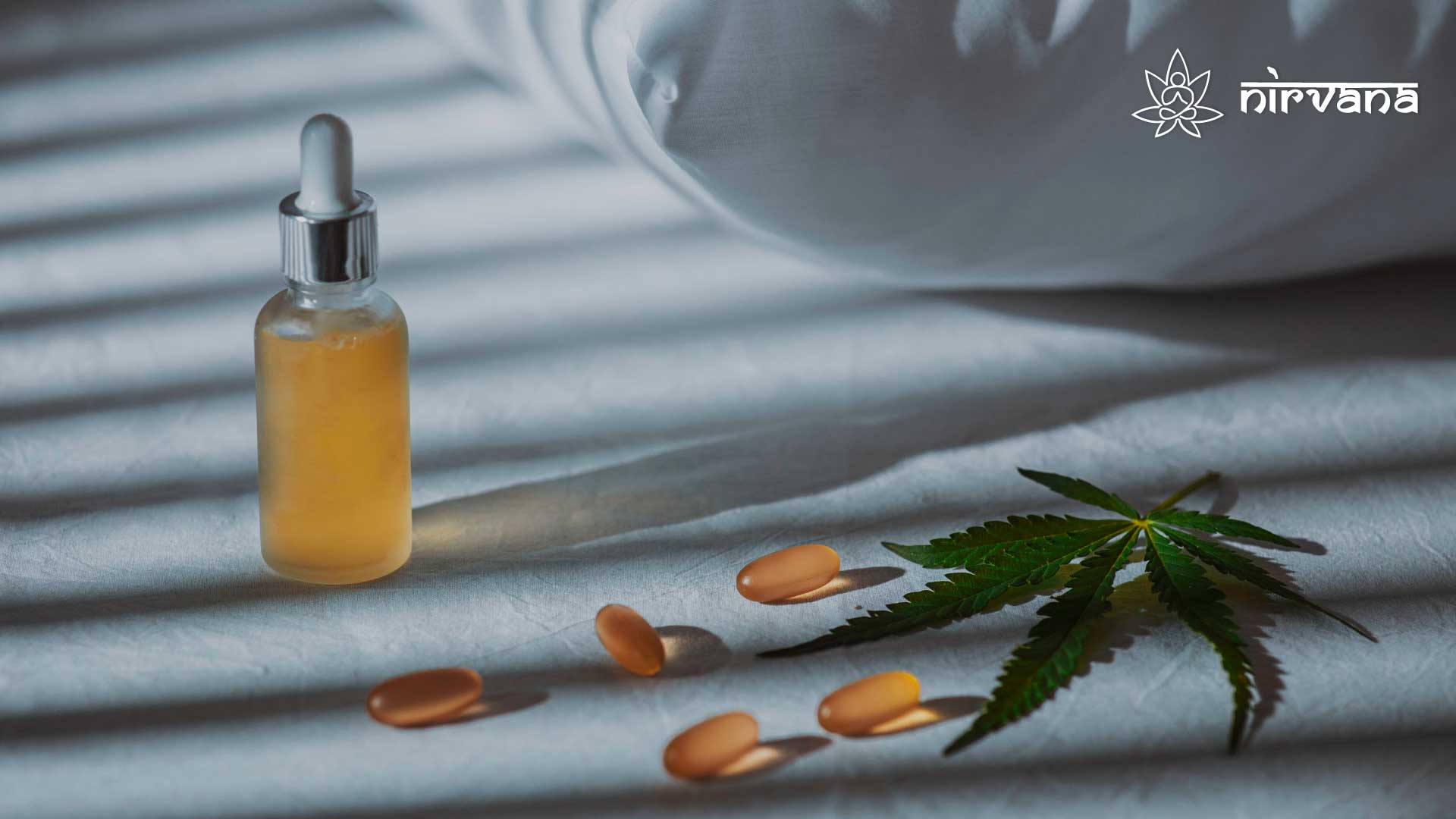 Cannabis oil, capsules, and leaf on a bed